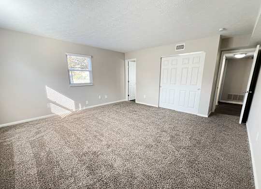 an empty living room with carpet and a white door