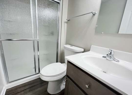 A white toilet sits next to a sink in a bathroom at Revere Village Apartments, Ohio, 45458