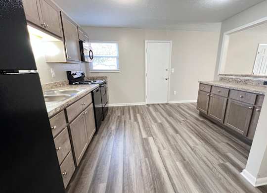 A kitchen with a black refrigerator and wooden floors at Revere Village Apartments, Centerville, Ohio