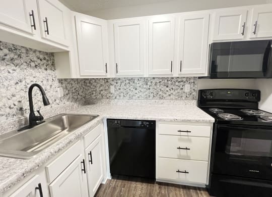 a kitchen with white cabinets and black appliances and a sink at 450 on Keeneland Apartments, Richmond, KY