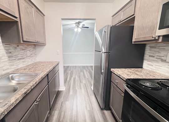 A kitchen with a black refrigerator and a stove top oven.