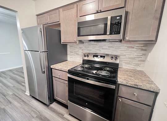 A kitchen with a stove, refrigerator, and microwave.
