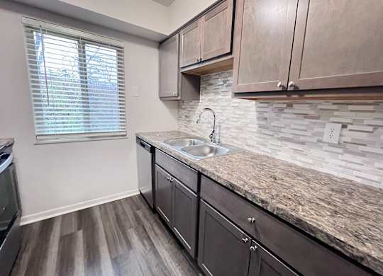 A kitchen with a granite countertop and wooden cabinets.