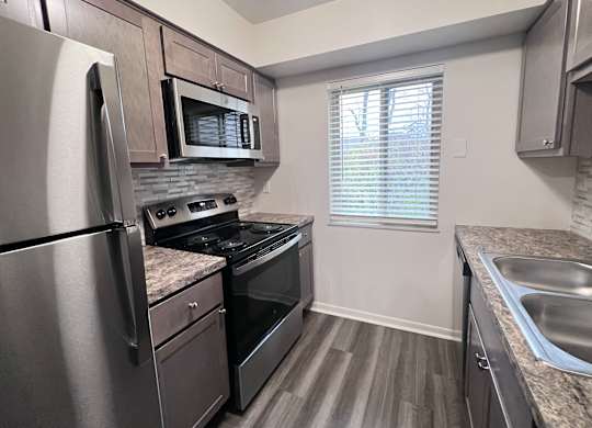 A kitchen with a stainless steel refrigerator, microwave, and oven.