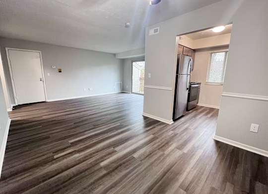 A room with wooden flooring and a refrigerator in the corner.