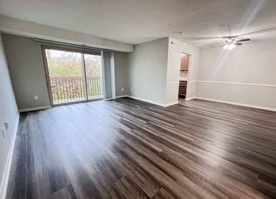 A room with wooden flooring and a sliding glass door.