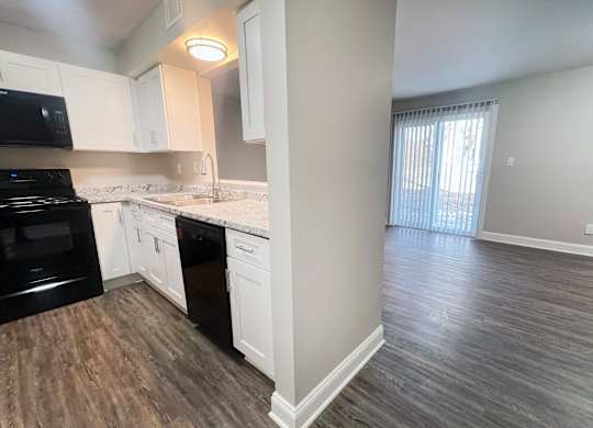 A kitchen with black appliances and white cabinets.