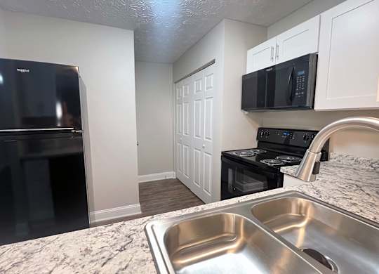 A kitchen with a black fridge, black oven, and black microwave.