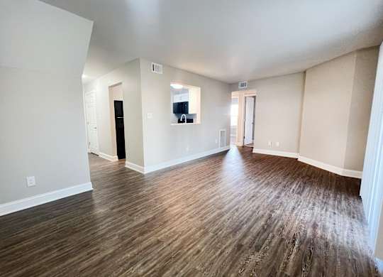 A room with wooden flooring and white walls.