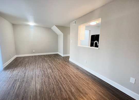 A room with wooden flooring and a mirror on the wall.