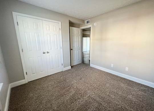 A room with a carpeted floor and two doors.