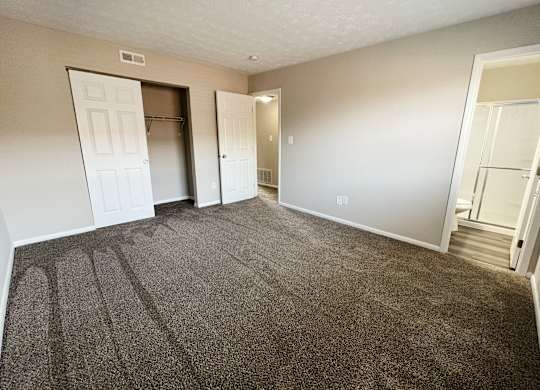 an empty living room with carpeting and a door to a closet at Revere Village Apartments, Ohio, 45458