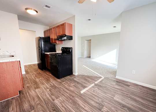 A kitchen with a black fridge and a wooden floor.