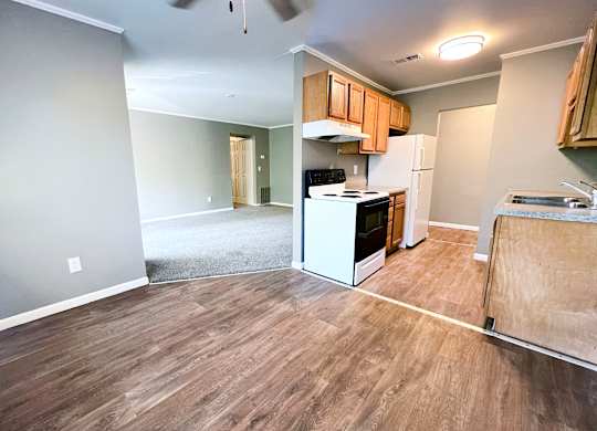 A kitchen with wood flooring and white appliances.