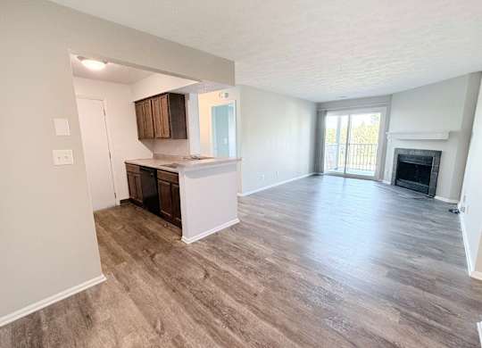 A spacious living room with a fireplace and a kitchen area in the background.