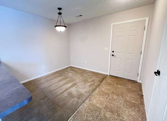 A room with a white door and a light hanging from the ceiling.