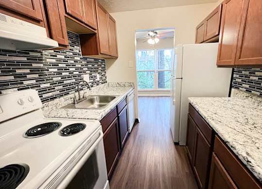A kitchen with white appliances and brown cabinets.