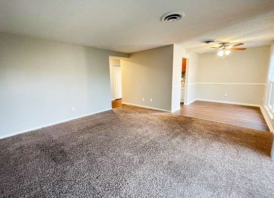 A room with a carpeted floor and a ceiling fan.