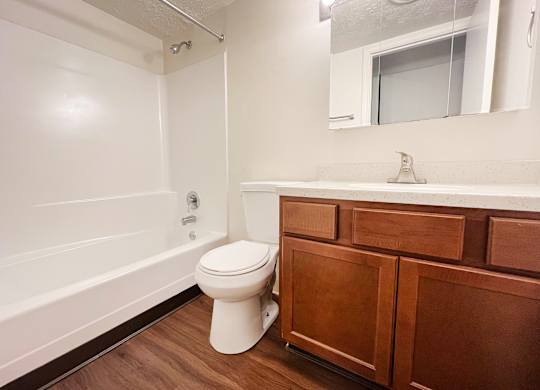 A white toilet sits in a bathroom next to a white bathtub.
