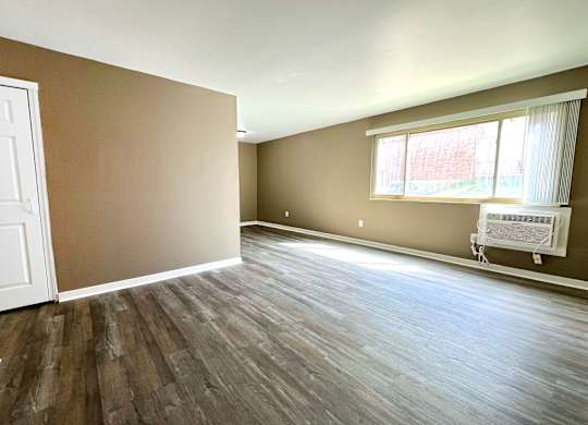 A room with brown walls and wooden flooring with a white door and window.