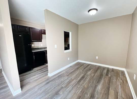 A kitchen with a black fridge and wooden flooring.