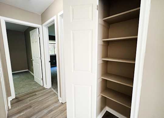 A white door is open to a room with a brown floor.