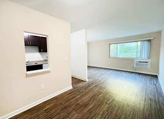 A room with wood flooring and a window with blinds.