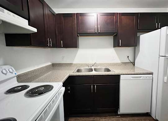 A kitchen with white appliances and dark brown cabinets.