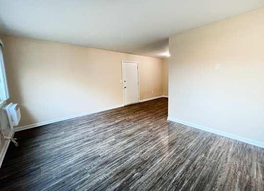 A room with wood flooring and a white door.