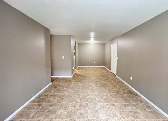 A long, empty hallway with tiled flooring and white walls.