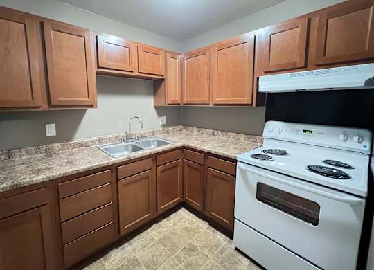 A kitchen with brown cabinets and a white stove.