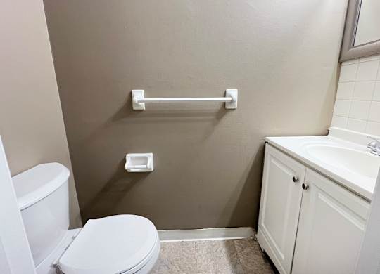 A white toilet sits next to a white sink in a small bathroom.