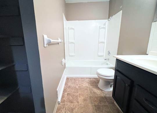 A bathroom with a toilet, sink, and a shower stall.