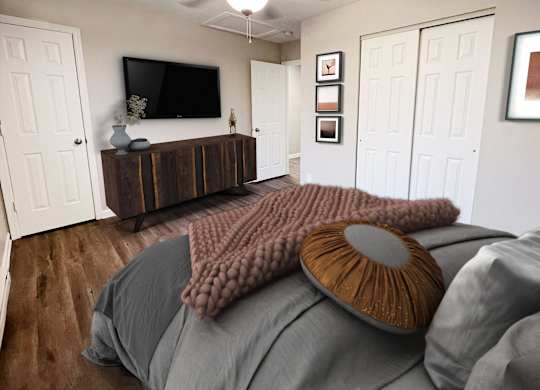 A bed with a grey comforter and a brown pillow with a round design on it.