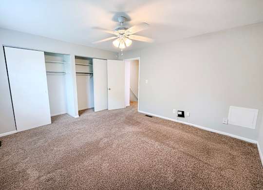A room with a ceiling fan and carpeted floor.