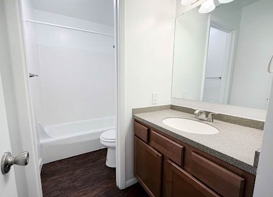 A white bathroom with a toilet, sink, and mirror.