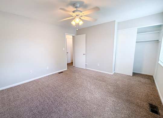 A room with a ceiling fan and carpeted floor.