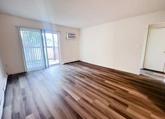 A room with wooden flooring and a sliding glass door.