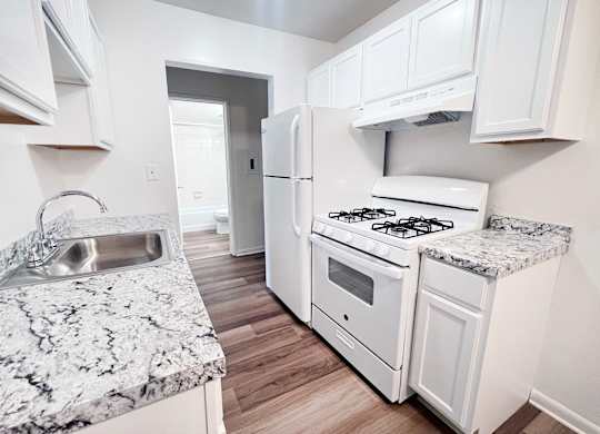 A kitchen with a granite counter top and white appliances.