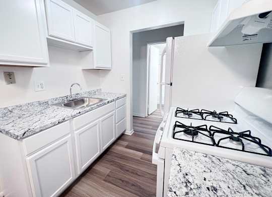 A kitchen with a marble countertop and white cabinets.