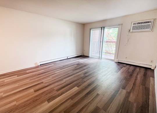 A room with wooden flooring and sliding glass doors.