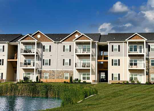 Three story apartment buildings with waterfront lawn at The Meridian on 32 Apartments, Batavia, OH 45103
