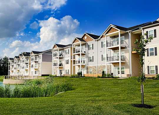 Multi story apartment buildings with pond and green lawn at The Meridian on 32 Apartments, Batavia, OH