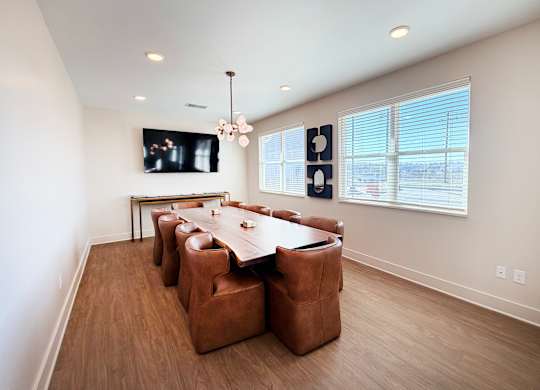 A conference room with a long table surrounded by brown chairs.