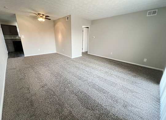 an empty living room with carpet and a ceiling fan at Revere Village Apartments, Centerville, OH, 45458