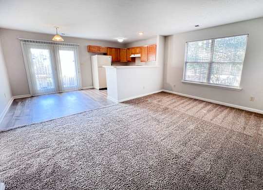 A spacious living room with a carpeted floor and a large window.