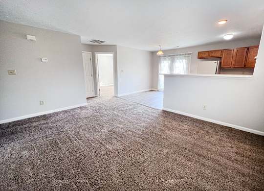 A large, empty room with carpeted flooring and white walls.