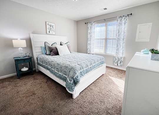 A bedroom with a large bed and a nightstand with a lamp.