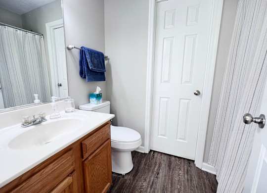 A white bathroom with a toilet, sink, and mirror.