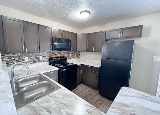 A kitchen with a black fridge and a black stove.